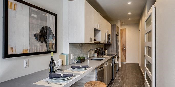 a kitchen with a long counter and a painting on the wall