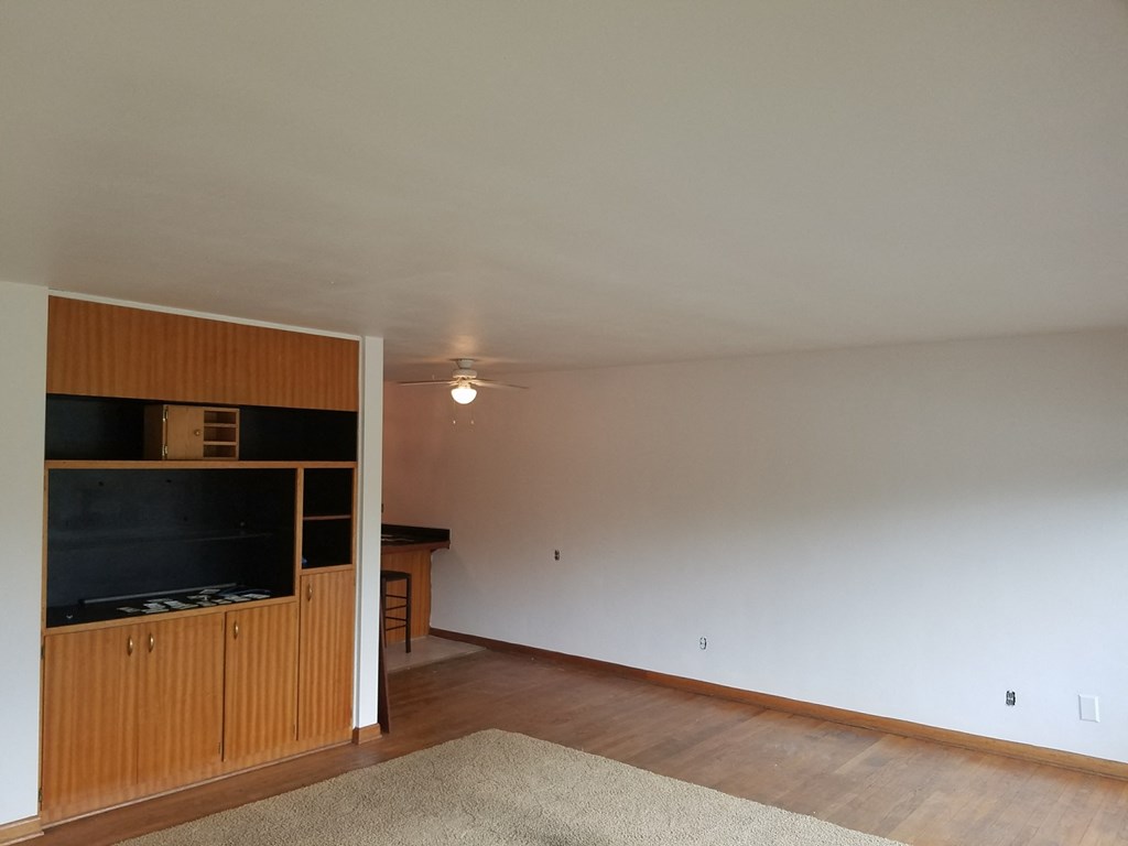 an empty living room with a ceiling fan and a tv