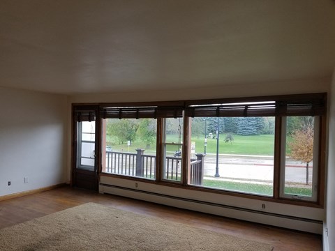 an empty living room with large windows and a rug