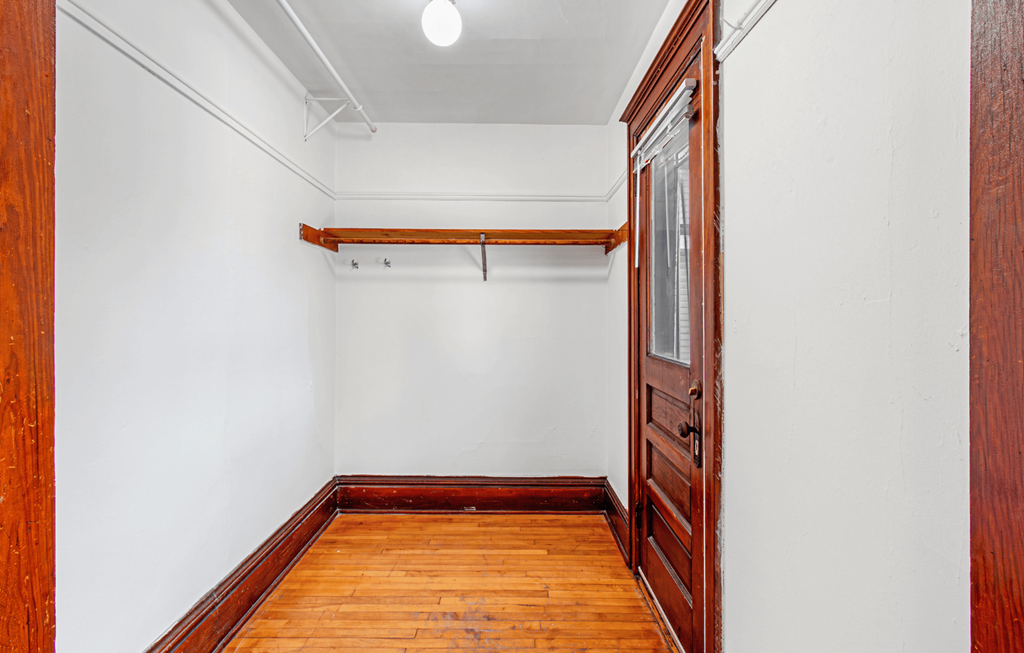 a room with wood floors and white walls and a wooden door