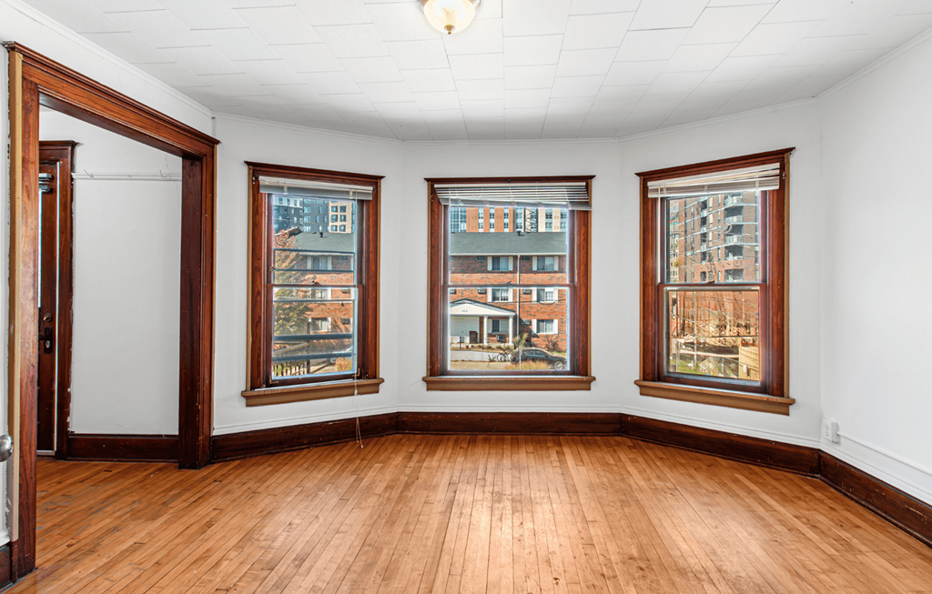 a living room with wood floors and four windows