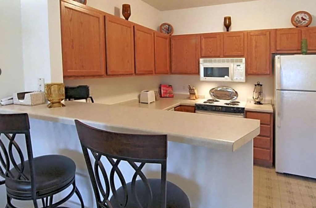 a kitchen with a counter with two chairs