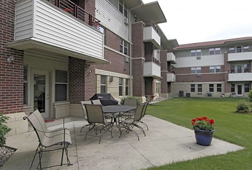 a patio with a table and chairs in front of a building