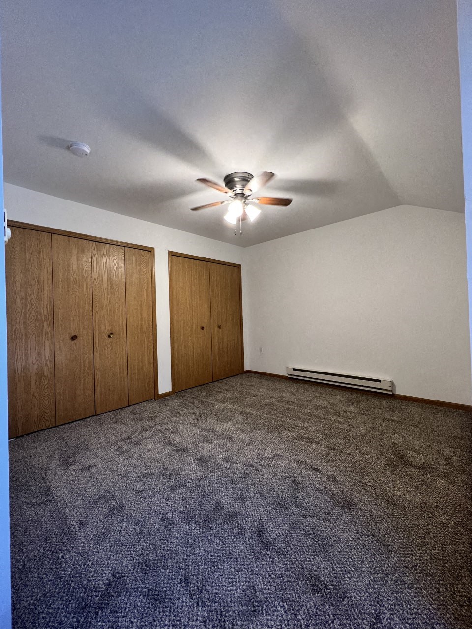 A room with a ceiling fan and two doors.