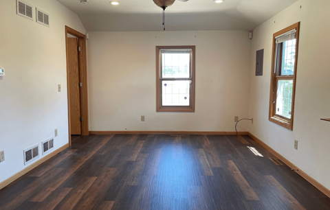 an empty living room with wood floors and a window
