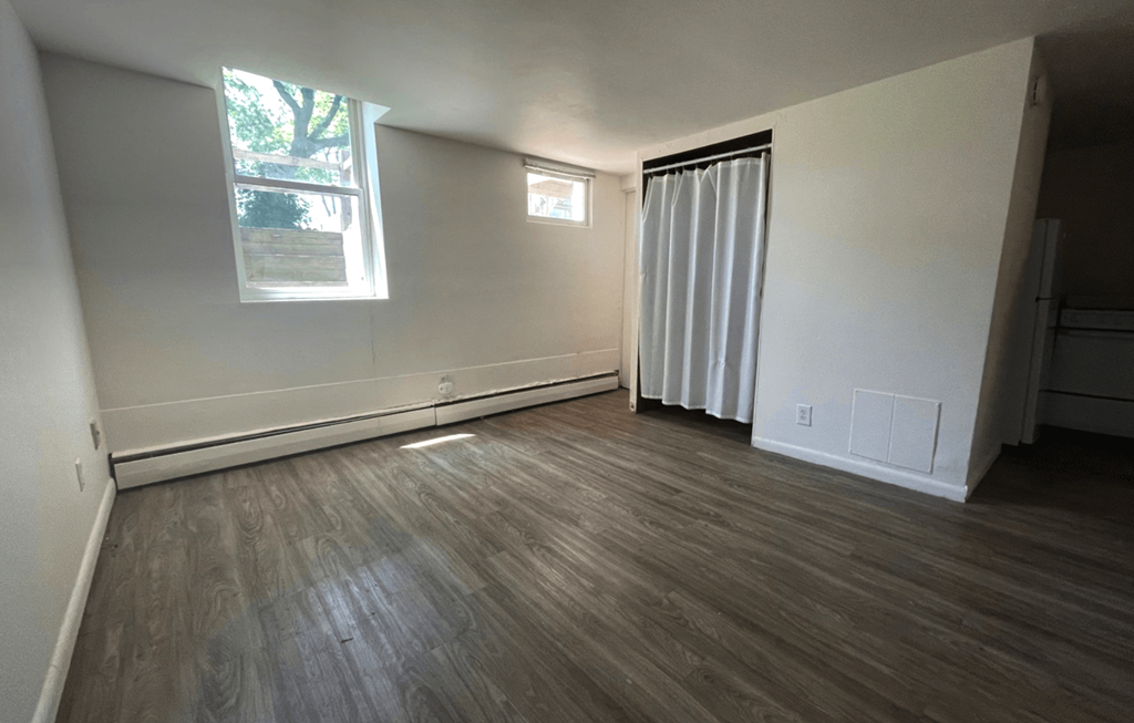 an empty living room with wood flooring and a window