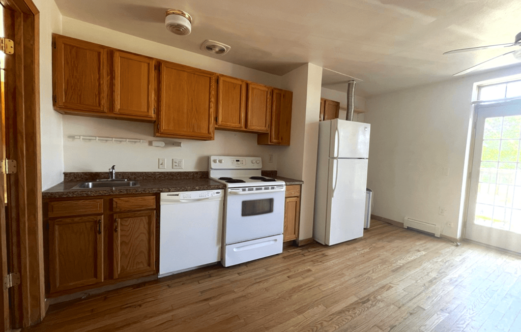 an empty kitchen with white appliances and wooden cabinets