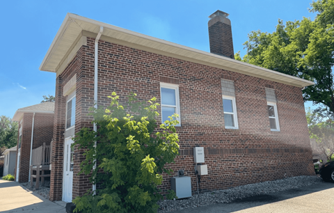 a brick building with a chimney and a tree in front of it