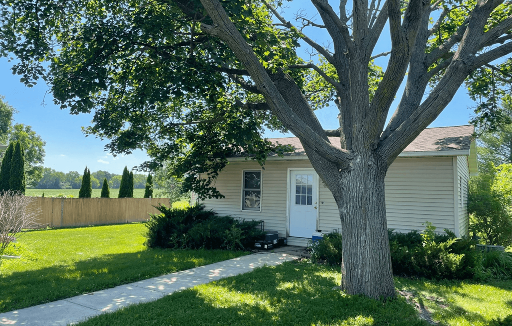 a small white house with a tree in front of it