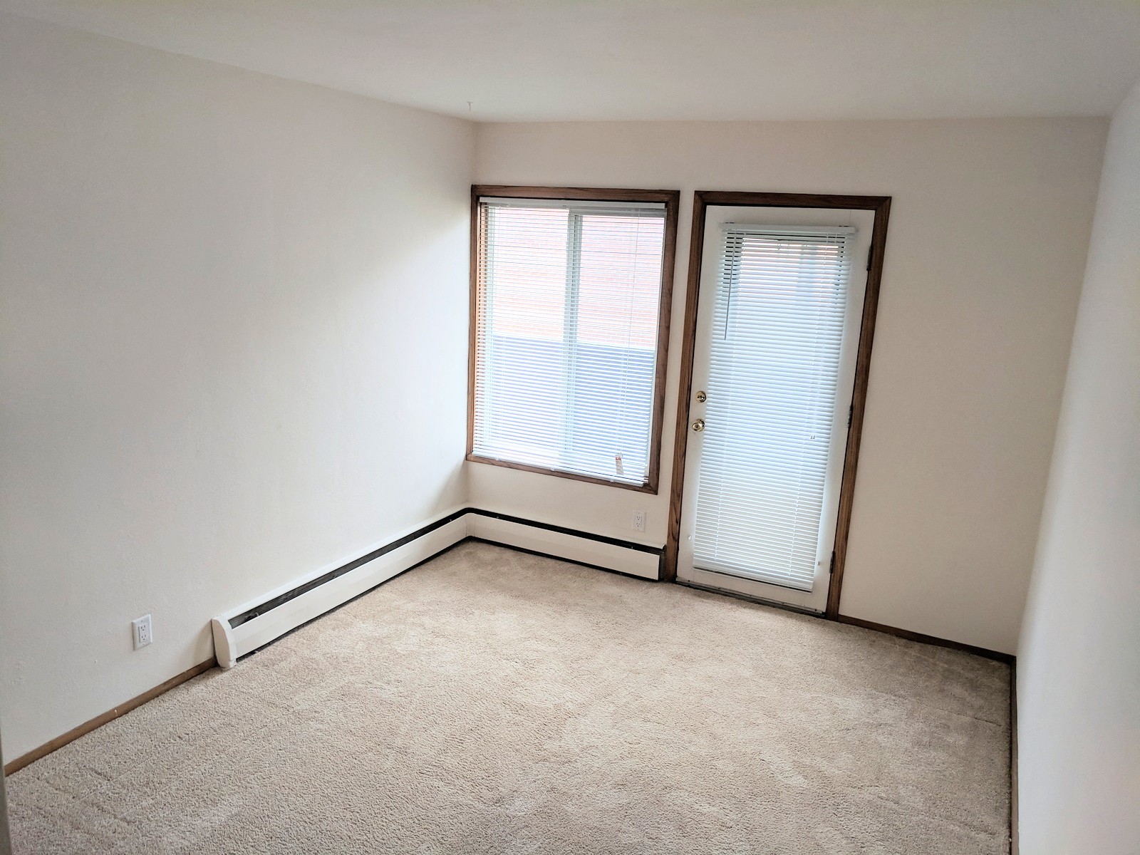 the living room of an empty house with white walls and a window with blinds