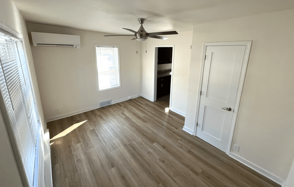 an empty living room with wooden floors and a ceiling fan