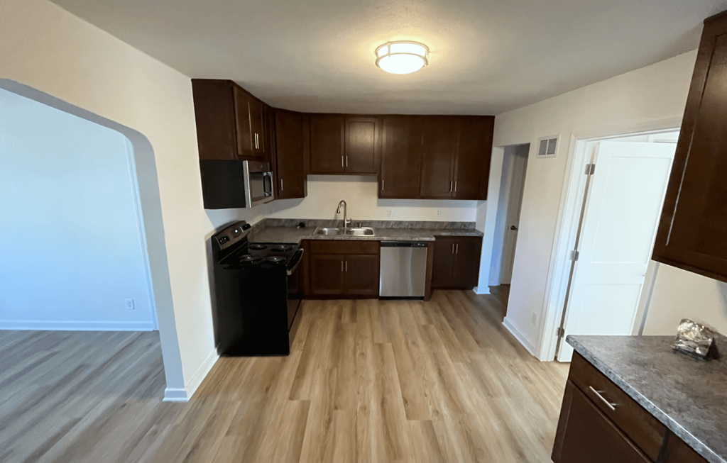 an empty kitchen with wood flooring and wooden cabinets