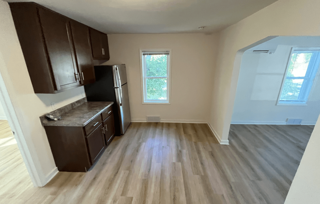 an empty kitchen with wooden floors and cabinets and a window
