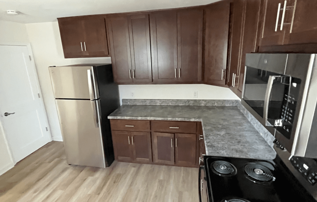 an empty kitchen with stainless steel appliances and wooden cabinets