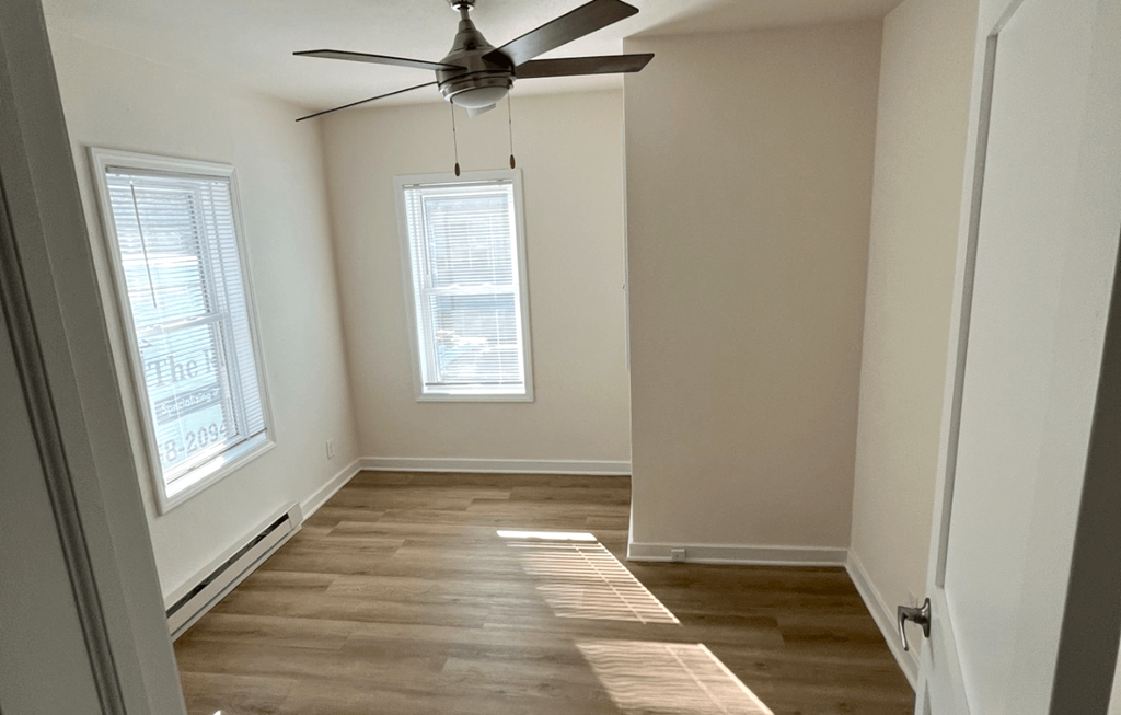 an empty room with a ceiling fan and two windows