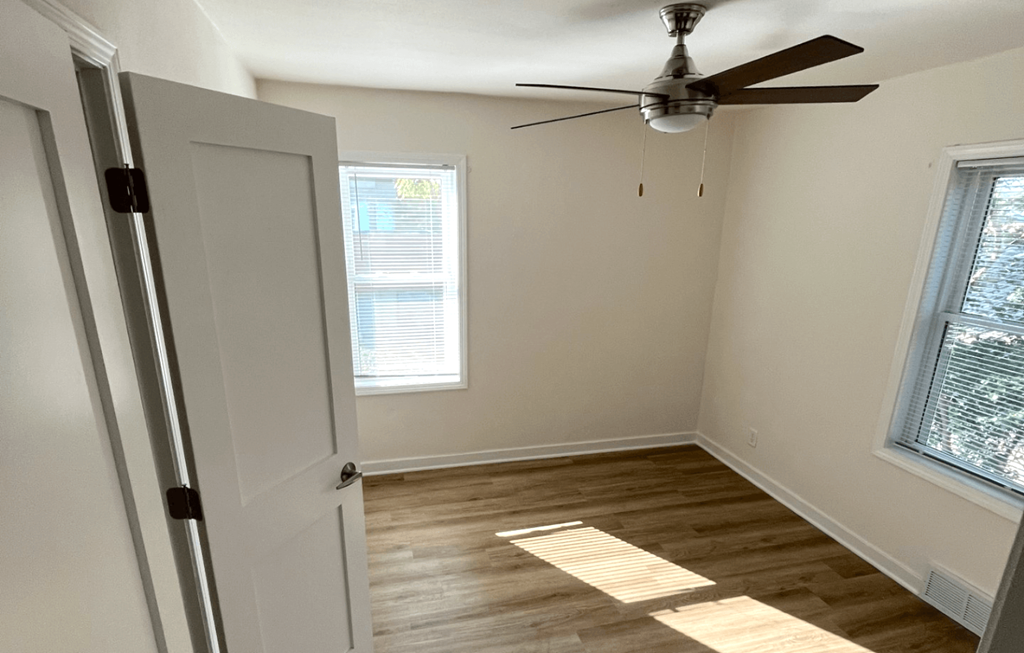 an empty room with a ceiling fan and a window