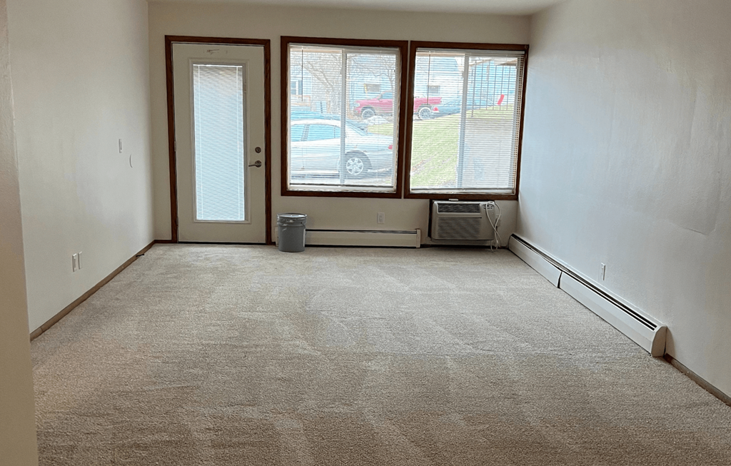 an empty room with a carpeted floor and three windows