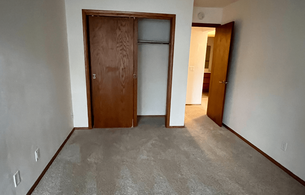 a room with a carpeted floor and a door to a closet