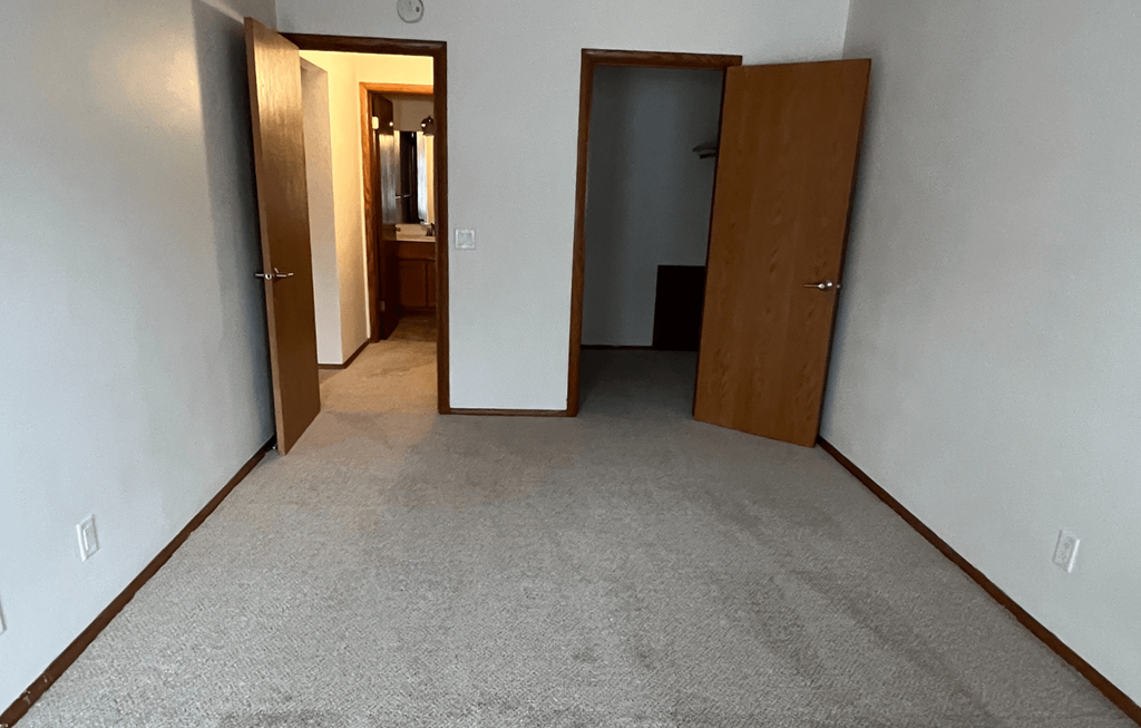 an empty room with three doors and a carpeted floor
