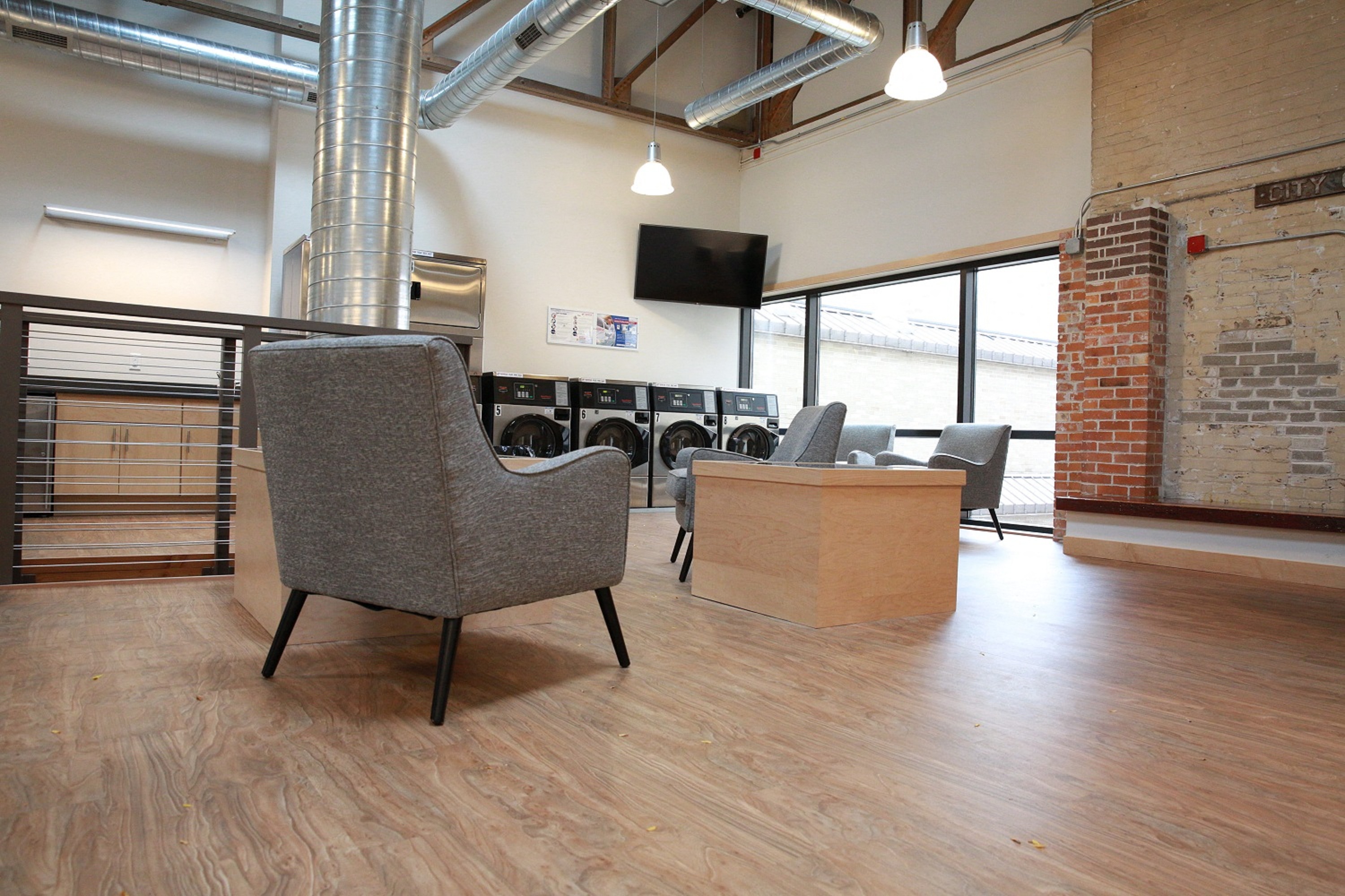 a lounge area with chairs and a tv in a room with a brick wall and