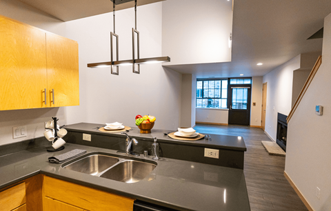 A modern kitchen with a black counter top and wooden cabinets.