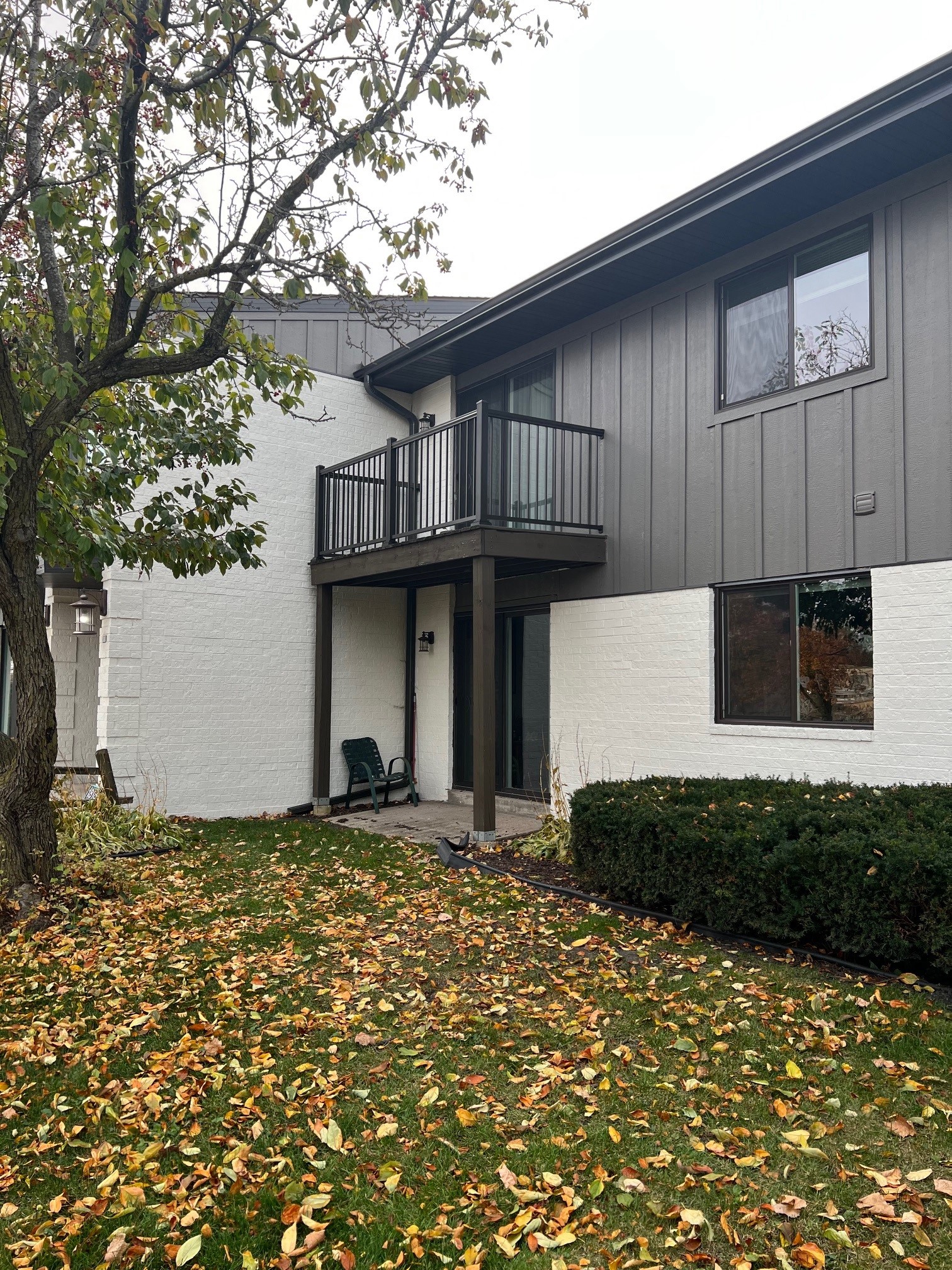 the exterior of a house with a balcony and a yard with fallen leaves
