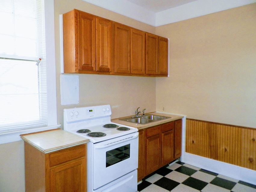 a kitchen with a stove and sink and wooden cabinets