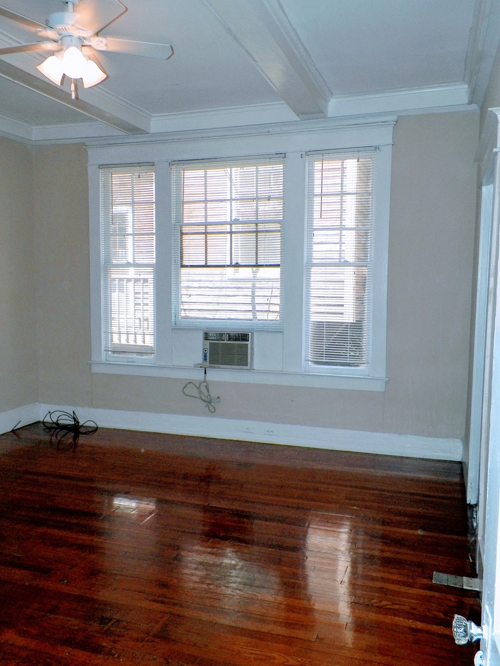 a living room with a hard wood floor and three windows