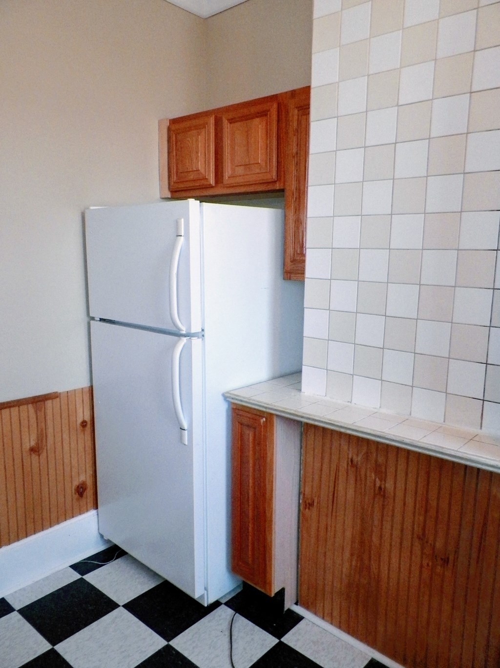 a kitchen with a white refrigerator and wooden cabinets