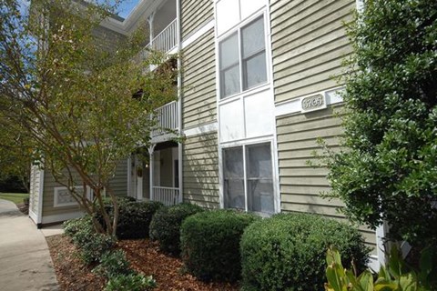 an apartment building with a sidewalk and bushes