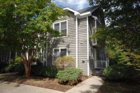 a gray house with a sidewalk and trees