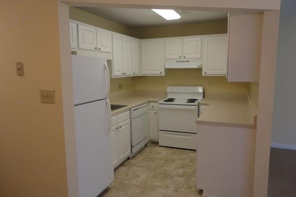 an empty kitchen with white appliances and white cabinets