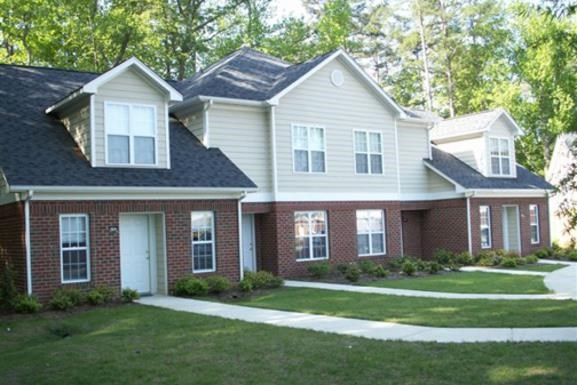 a brick house with white and black siding and a lawn