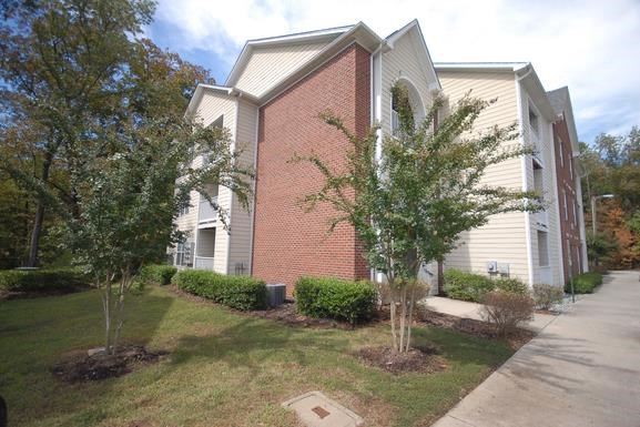 a building with a sidewalk and trees in front of it