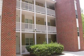 an apartment building with a balcony and a red brick wall