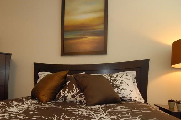 a bed with pillows and a painting on the wall