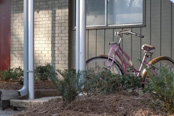 a pink bike parked in front of a building