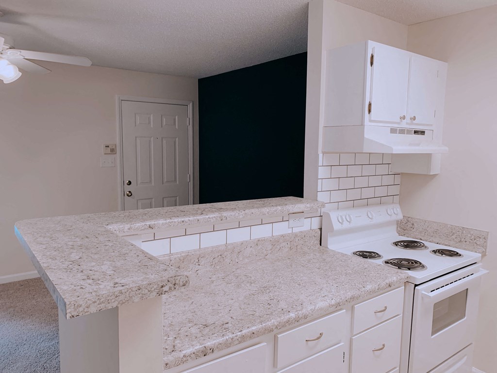an empty kitchen with white appliances and granite counter tops