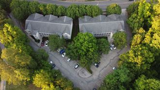 arial view of a house with a parking lot and trees