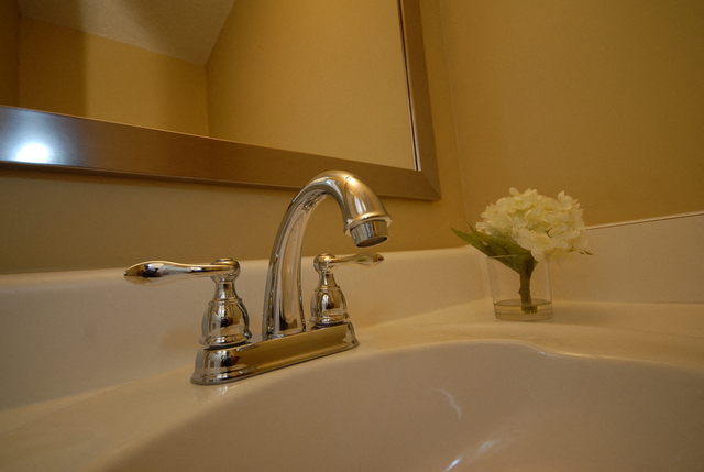 a bathroom with a sink and a vase with a flower