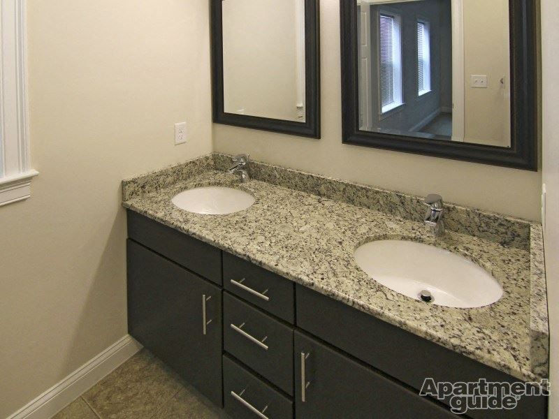 a bathroom with two sinks with granite counter tops and two mirrors