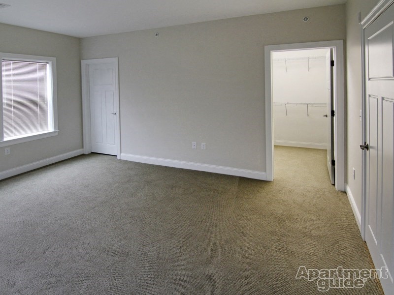 a bedroom with a carpeted floor and a door to a closet