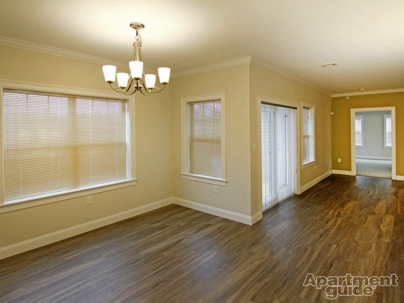 an empty living room with wood floors and a chandelier