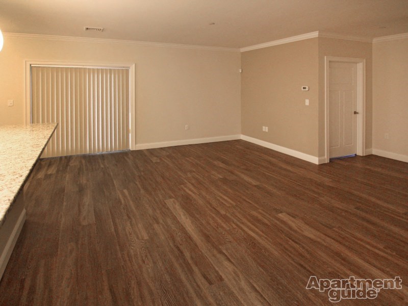an empty living room with wood flooring and a door to a closet