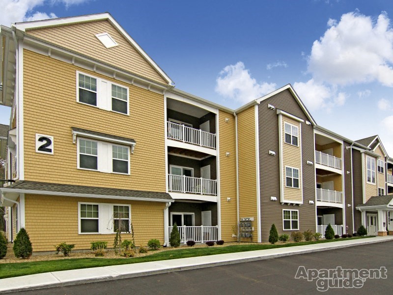 a street view of an apartment building with yellow siding