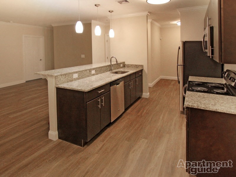 an empty kitchen with wooden floors and granite counter tops