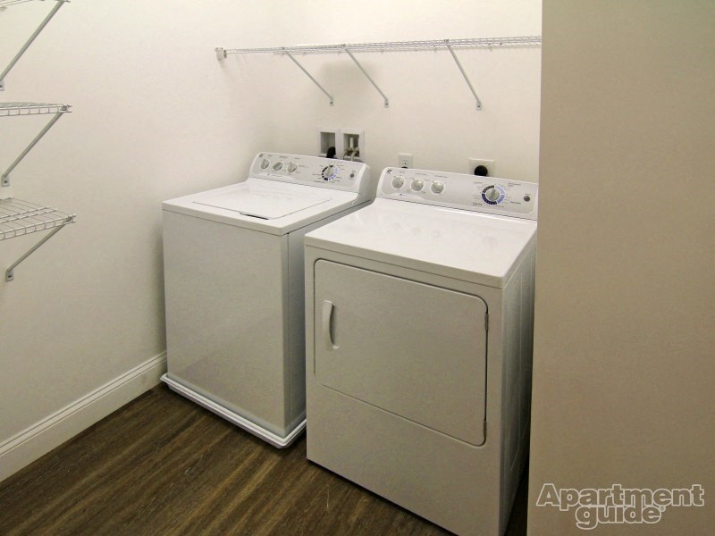 a washer and dryer in a room with a white wall and wood floor