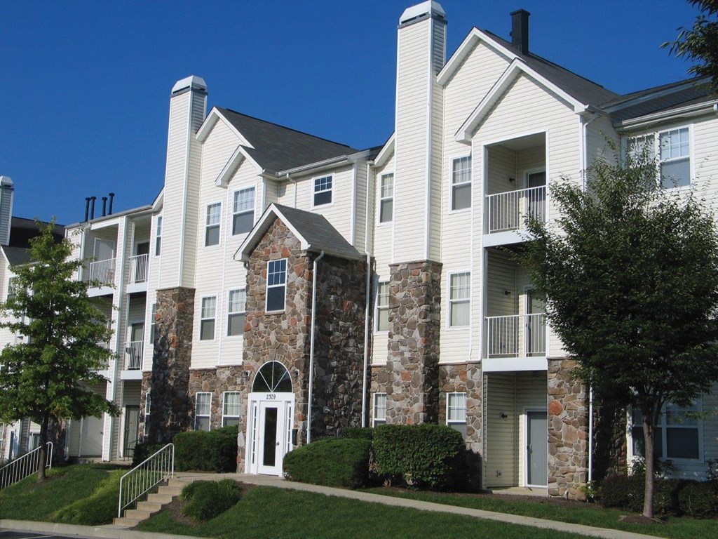 an exterior view of a large apartment building with trees and grass