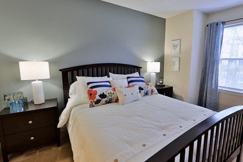 a bedroom with a bed and two lamps and a window