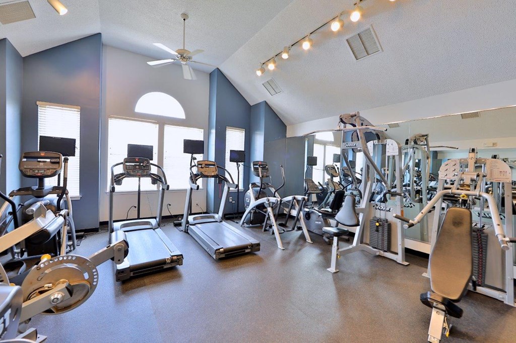 a gym with cardio equipment and windows